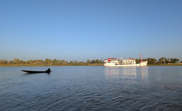 bateau de croisière Bou el Mogdad sur le fleuve Sénégal en arrière plan et une pirogue au premier plan